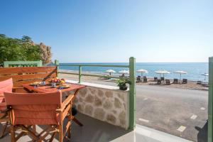 een balkon met een tafel en stoelen en het strand bij EGLI LUXURY APARTMENTS in Archangelos