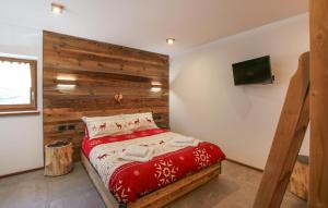 a bedroom with a red bed with a wooden wall at Awesome Home In Castello Tesino With Kitchen in Castello Tesino