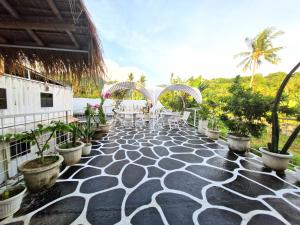 a resort patio with tables and chairs and palm trees at Karcof Container Hostel in Senggigi 