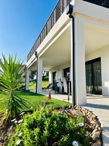 une maison avec une terrasse couverte dotée de chaises et d'un palmier dans l'établissement Bas de villa avec jardin idéalement situé entre Ajaccio et Porticcio, à Bastelicaccia