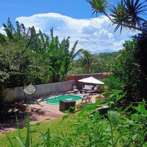 a backyard with a pool and a table and chairs at Namorada Brava Guest House in Búzios
