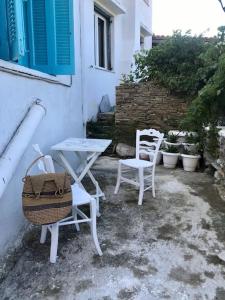 2 chaises blanches, une table, une table et des chaises dans l'établissement La maison du Pêcheur, à Kourélion