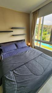 a bedroom with a large blue bed with a window at Plus condominium 2 kathu in Ban Thung Thong