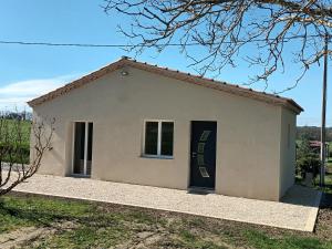 een klein wit huis met een deur in een veld bij Petite Maison dans le Gers 32 in Mouchan