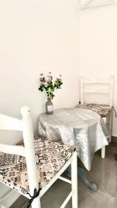 una habitación con 2 sillas blancas y una mesa con una planta en JARA HOME Malaga Centro en Málaga