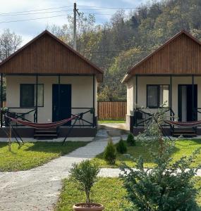 a small house with a hammock in front of it at Flora Racha - Lovely Cottages in Ambrolauri