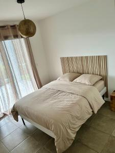 un letto in una camera da letto con finestra e lampada di Bas de villa avec jardin idéalement situé entre Ajaccio et Porticcio a Bastelicaccia