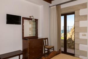 a bedroom with a dresser and a mirror and a window at Fotini Traditional Villas in Kavoúsion