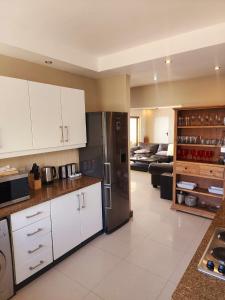 a kitchen with white cabinets and a stainless steel refrigerator at Bikini Beach Manor in Gordonʼs Bay