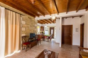an open living room with a stone wall and wooden ceilings at Fotini Traditional Villas in Kavoúsion