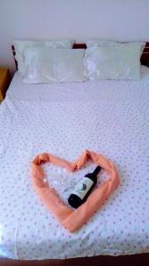 a bottle of wine in a heart shaped towel on a bed at Hotel Markovi Kuli TD in Prilep