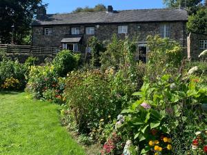 une ancienne maison en pierre avec un jardin fleuri dans l'établissement Pant-y-creolen, à Llanfyllin