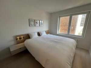 a bedroom with a large white bed and a window at ASTRID 0301 - App voor 6 personen in De Panne