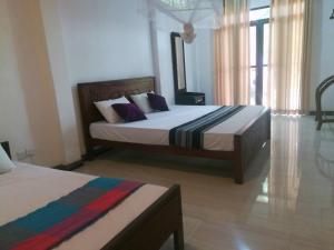 a bedroom with two beds and a window at Tezara Home Stay in Sigiriya