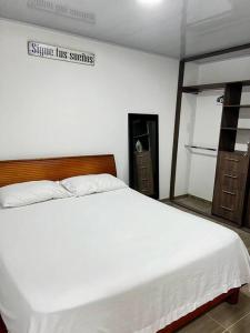 een slaapkamer met een wit bed en een bord aan de muur bij Aparta estudio en Acacias - Meta in Acacías
