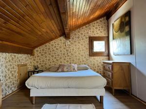 una camera da letto con un letto e un soffitto in legno di Au Petit Bonheur a Camprieu