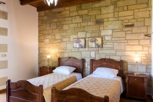 two beds in a room with a stone wall at Fotini Traditional Villas in Kavoúsion +49 photos