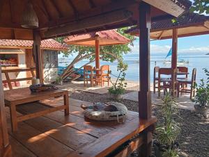 a person is laying on a wooden table on a deck at Pelangi Homestay Bungalow Gili gede in Sekotong