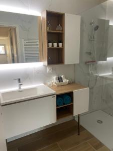 a white bathroom with a sink and a mirror at La Palmeraie 2 chambres in Sainte-Maxime
