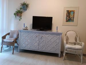 a television on a dresser in a living room with two chairs at La Casetta - Near the sea & free parking in Rapallo