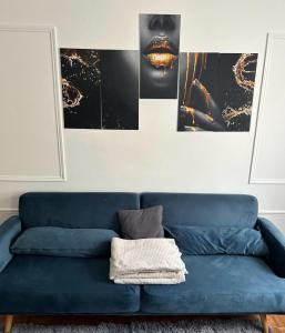 um sofá azul numa sala de estar com fotografias na parede em Luxury Appartement Batignole em Paris