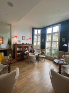 a living room with chairs and tables and windows at Hôtel & Espace Bien-être La Maison du Lierre in Biarritz