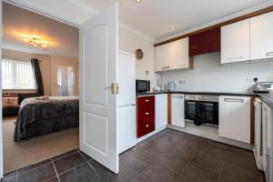 eine Küche mit weißen Schränken und ein Bett in einem Zimmer in der Unterkunft Airstays Apartment in Wythenshawe