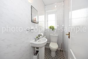 a white bathroom with a toilet and a sink at Airstays Apartment in Wythenshawe