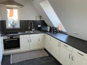 a kitchen with white cabinets and a black counter top at Jenszu Ferienwohnung in Balingen