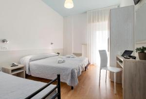 a bedroom with two beds and a desk with a television at Hotel Kursaal in Bellaria-Igea Marina