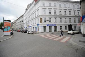 um homem a atravessar uma rua em frente a um edifício branco em Lovely Renovated Apartment Top 11 - Easy Self Check in em Viena