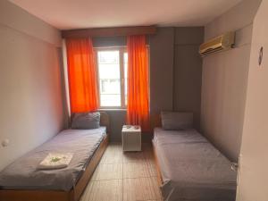Pokój z 2 łóżkami i oknem z pomarańczowymi zasłonami w obiekcie Ersoy Ak Pansiyon w mieście Antalya