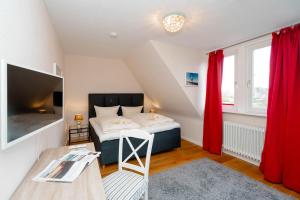 a bedroom with a bed with red curtains and a table at Ferienhaus Sprotte in Tinnum