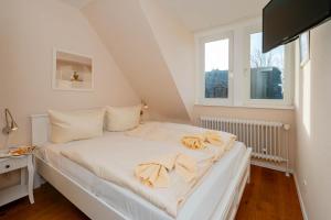 ein weißes Bett in einem Zimmer mit 2 Fenstern in der Unterkunft Ferienhaus Sprotte in Tinnum