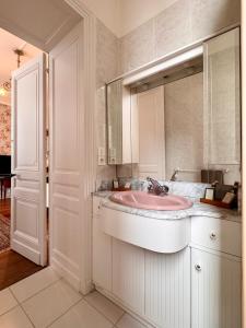 baño con lavabo rosa y espejo en Chateau Moncassin, en Leyritz-Moncassin