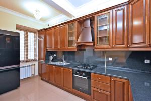 une cuisine avec des armoires en bois et un four à plaques de cuisson dans l'établissement Lux Apartment 2 Bedroom, 2 Open Balcony In The Center Of Yerevan, Near Republic Square, à Erevan