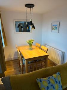 a dining room table with chairs and a vase of flowers at Citrus Chalet, modern light and airy! in Redruth