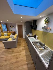 a kitchen with a sink and a couch in a room at Citrus Chalet, modern light and airy! in Redruth