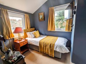 a small bedroom with a bed and two windows at Archway House in Grantham