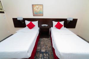 two beds in a hotel room with red pillows at فندق دار الريس - Dar Raies Hotel in Makkah