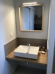 La salle de bains est pourvue d'un lavabo blanc et d'un miroir. dans l'établissement Au coeur d'Omaha Beach- Colleville-sur-Mer- Gîte 2, à Colleville-sur-Mer