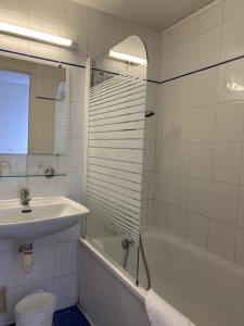 La salle de bains blanche est pourvue d'un lavabo et d'une baignoire. dans l'établissement SHELDER Hôtel - CHERBOURG EN COTENTIN - Equeurdreville, à Cherbourg en Cotentin