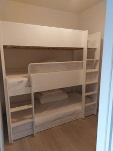 ニーウポールトにあるGelijkvloers vakantie-appartement met groot zonnig terrasの白い二段ベッドが備わる客室です。