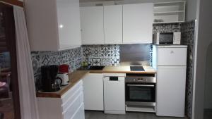 a kitchen with white cabinets and a white refrigerator at CHALET B NATURISTe MAEVA in Le Porge