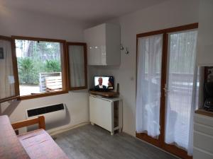 ein Wohnzimmer mit einem TV und einigen Fenstern in der Unterkunft CHALET B NATURISTE NAEVA in Le Porge