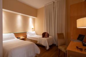 a hotel room with two beds and a chair at Hotel Iris in Genoa
