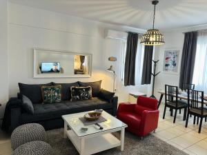 a living room with a black couch and a red chair at Gianna’s apartment central Aigio Cozy and Shining in Aígio