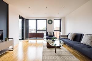 uma sala de estar com um sofá azul e uma mesa de vidro em The Sloane Apartment em Londres