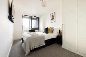 um quarto branco com uma cama e uma janela em The Sloane Apartment em Londres