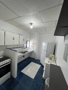 a kitchen with white appliances and blue tile floors at Hospedaje El Descanso CERCA CONSULADO AMERICANO GUAYQUIL in Guayaquil